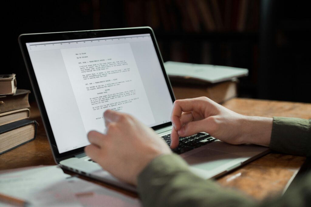 A person typing on a laptop in a cozy workspace with books around. Perfect for writing and technology themes.